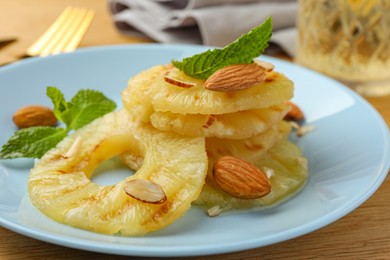 Photo of Tasty grilled pineapple slices, almonds and mint on table, closeup