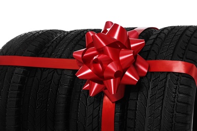 Photo of Winter tires with red ribbon on white background, closeup