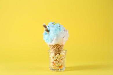 Sweet cotton candy in waffle cone on yellow background