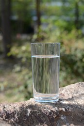 Photo of Glass of cool water on stone outdoors