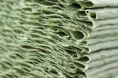 Texture of stacked light green paper napkins as background, macro view