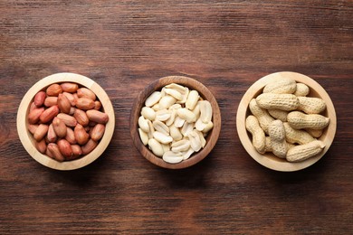 Photo of Fresh peanuts in bowls on wooden table, top view