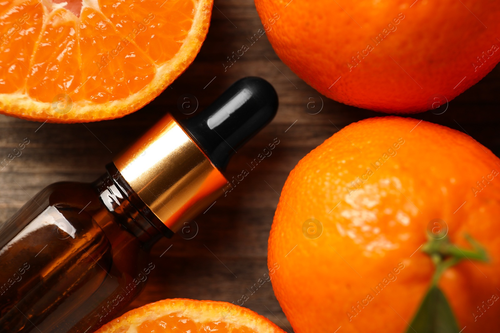 Photo of Bottle of tangerine essential oil and fresh fruits on wooden table, top view