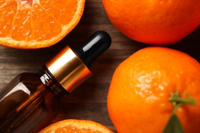 Photo of Bottle of tangerine essential oil and fresh fruits on wooden table, top view