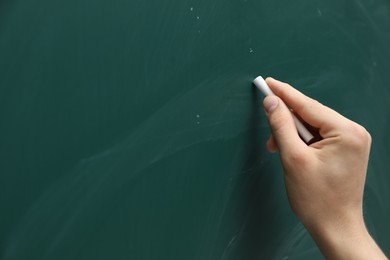 Photo of Teacher writing with chalk on green chalkboard, closeup. Space for text