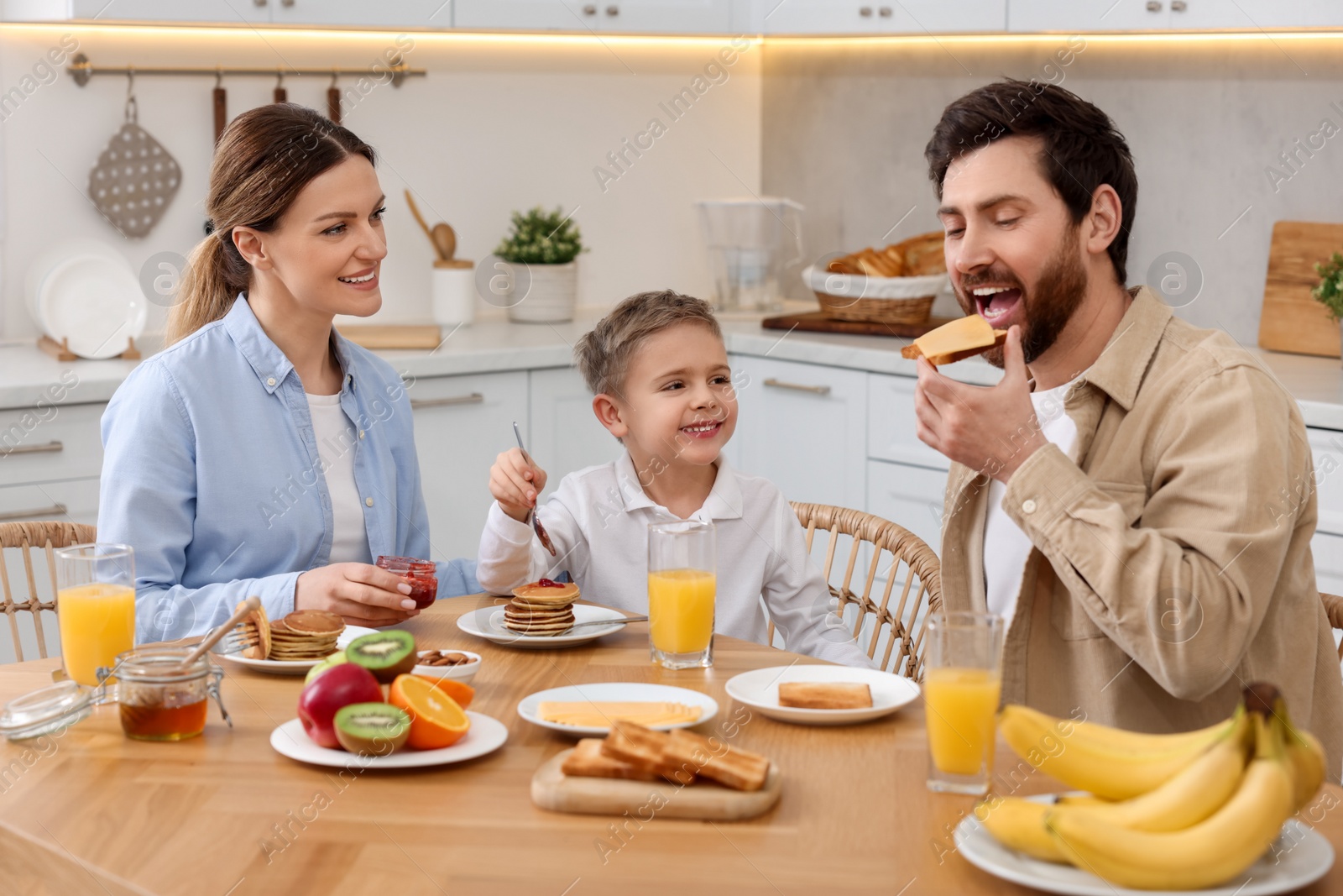 Photo of Happy family having breakfast at table in kitchen