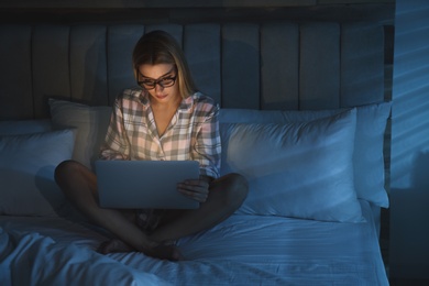 Photo of Young woman using laptop in bed at night. Sleeping disorder problem