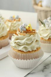 Photo of Tasty Easter cupcakes with vanilla cream on white marble table