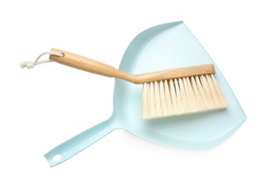 Photo of Light blue dustpan and wooden brush on white background, top view