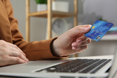 Photo of Online payment. Woman with credit card using laptop indoors, closeup