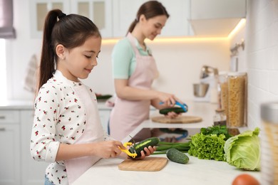 Mother and daughter peeling vegetables at kitchen counter