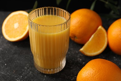 Photo of Tasty fresh oranges and juice on black table, closeup