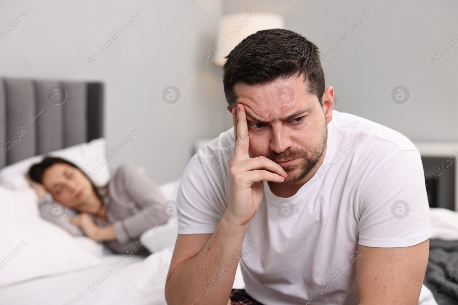 Photo of Stressed husband after quarrel with his wife in bedroom, selective focus. Relationship problems