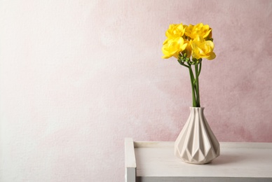 Bouquet of spring freesia flowers in vase on color background. Space for text