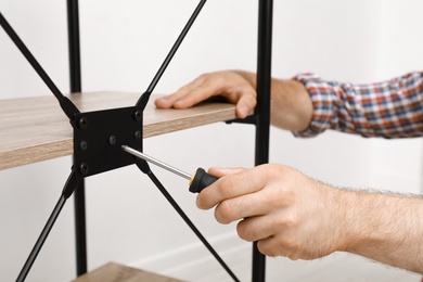 Photo of Man assembling modern rack in room, closeup