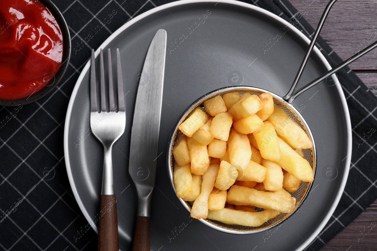 Photo of Tasty french fries and ketchup served on wooden table, flat lay