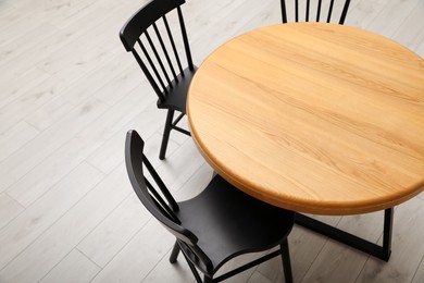 Stylish round table with black chairs on floor, above view