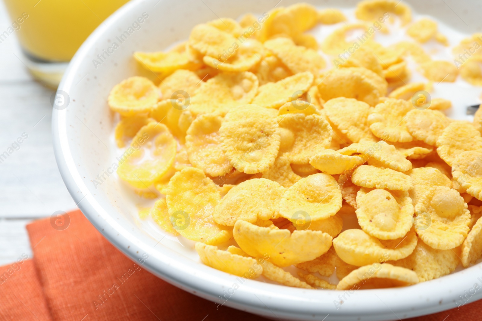 Photo of Tasty corn flakes with milk on white table, closeup