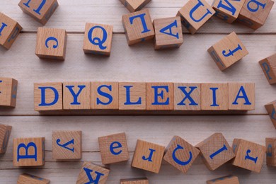 Photo of Cubes with word Dyslexia on wooden table, flat lay