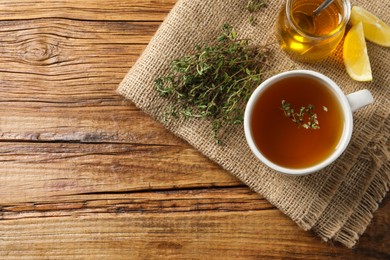 Aromatic herbal tea with thyme, honey and lemons on wooden table, top view. Space for text