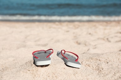 Striped flip flops on sandy beach near sea