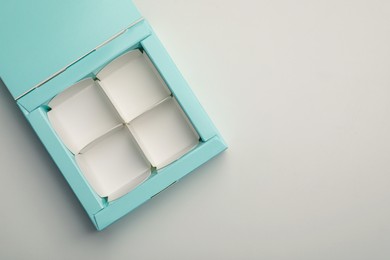 Photo of Empty turquoise candy box on light grey background, top view. Space for text