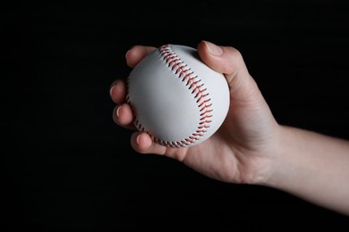 Baseball player holding ball on black background, closeup. Sports game