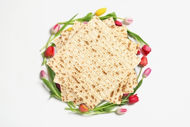 Image of Tasty matzos and flowers on white background, top view. Passover (Pesach) celebration