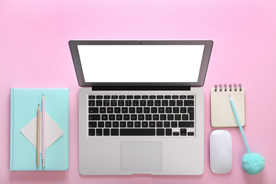 Photo of Modern laptop and office stationery on pink background, flat lay