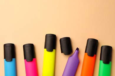 Bright color markers on beige background, flat lay. Space for text