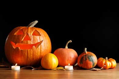 Halloween pumpkin head jack lantern and autumn decorations on table against dark background