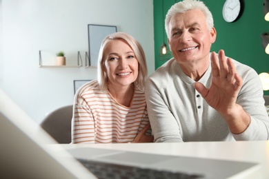 Photo of Mature couple using video chat on laptop at home