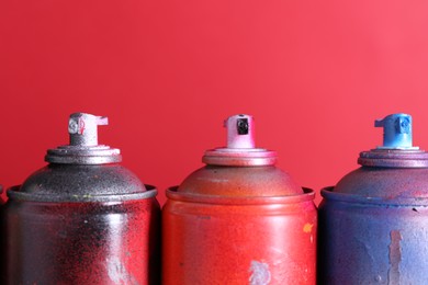 Photo of Many spray paint cans on red background, closeup. Space for text