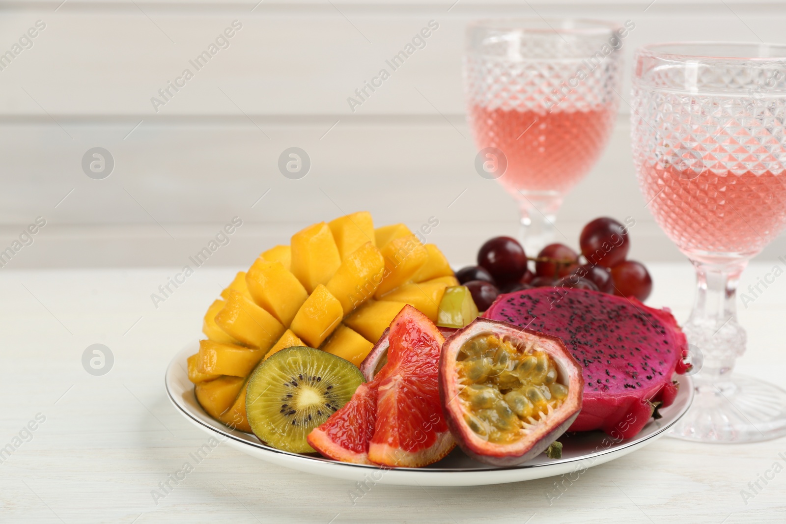 Photo of Delicious exotic fruits and wine on white wooden table