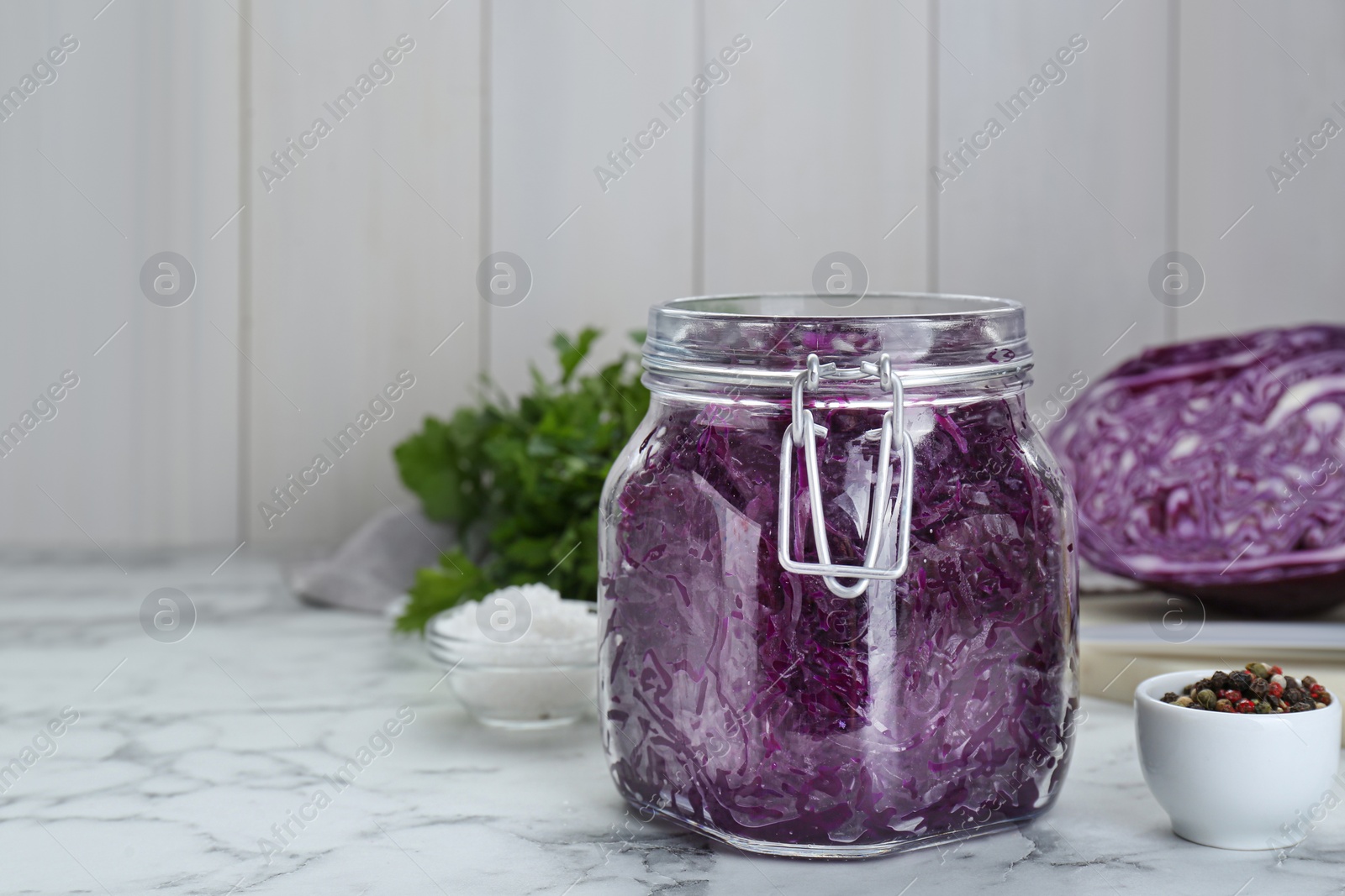 Photo of Tasty red cabbage sauerkraut and ingredients on white marble table. Space for text