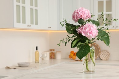 Photo of Beautiful pink hortensia flowers in vase on kitchen table. Space for text