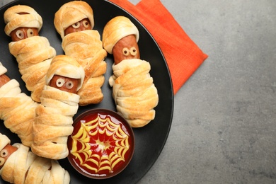 Photo of Spooky sausage mummies for Halloween party served on grey table, top view. Space for text