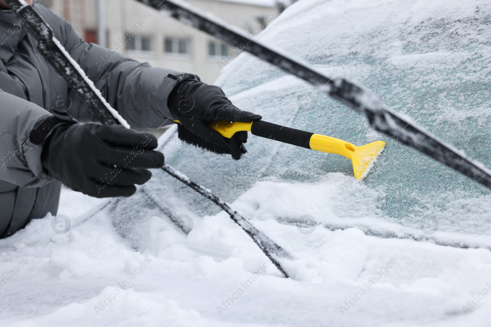 Photo of Man cleaning snow from car windshield outdoors, closeup