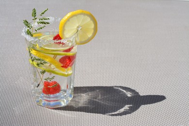 Photo of Delicious refreshing lemonade with raspberries on light gray rattan surface, space for text