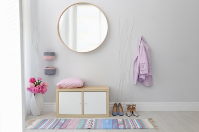 Stylish hallway interior with round mirror on white wall