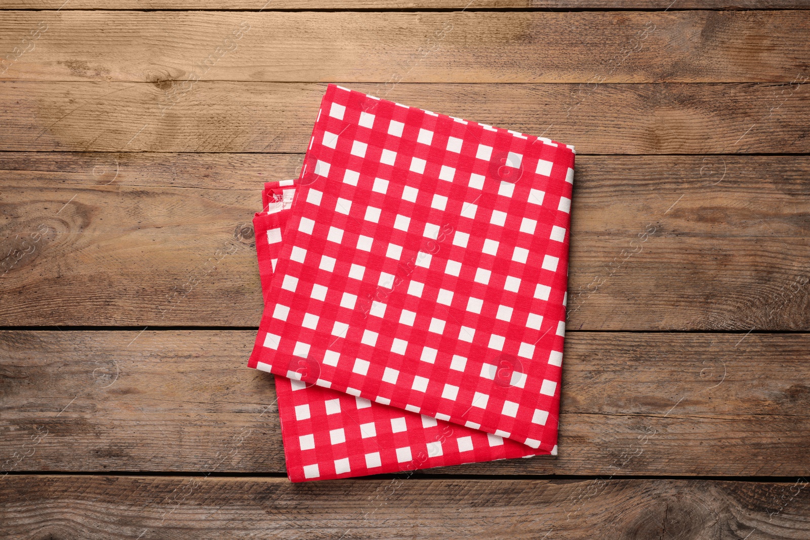 Photo of Checkered tablecloth on wooden table, top view