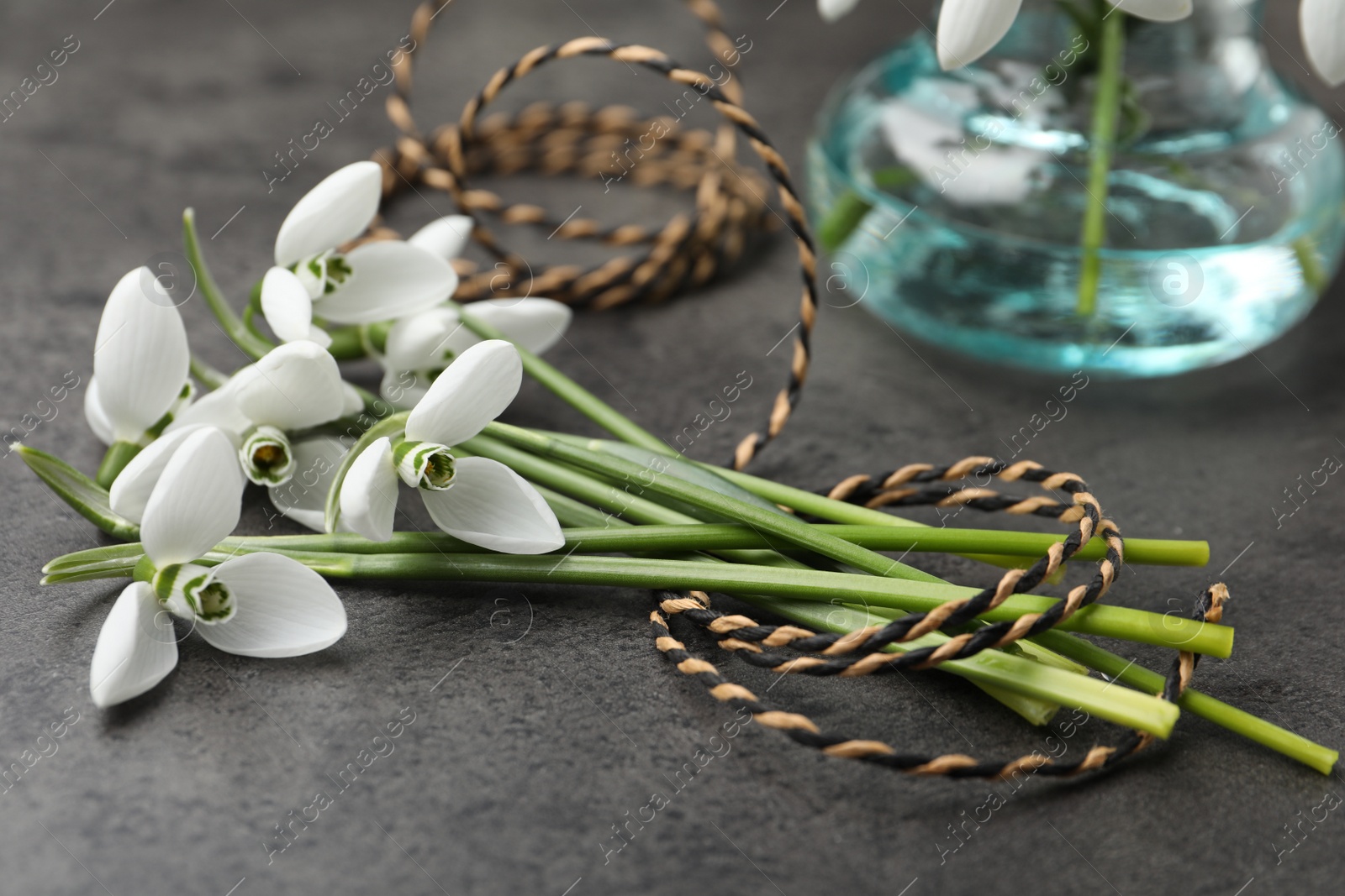 Photo of Beautiful snowdrops and twine on grey table. Spring flowers
