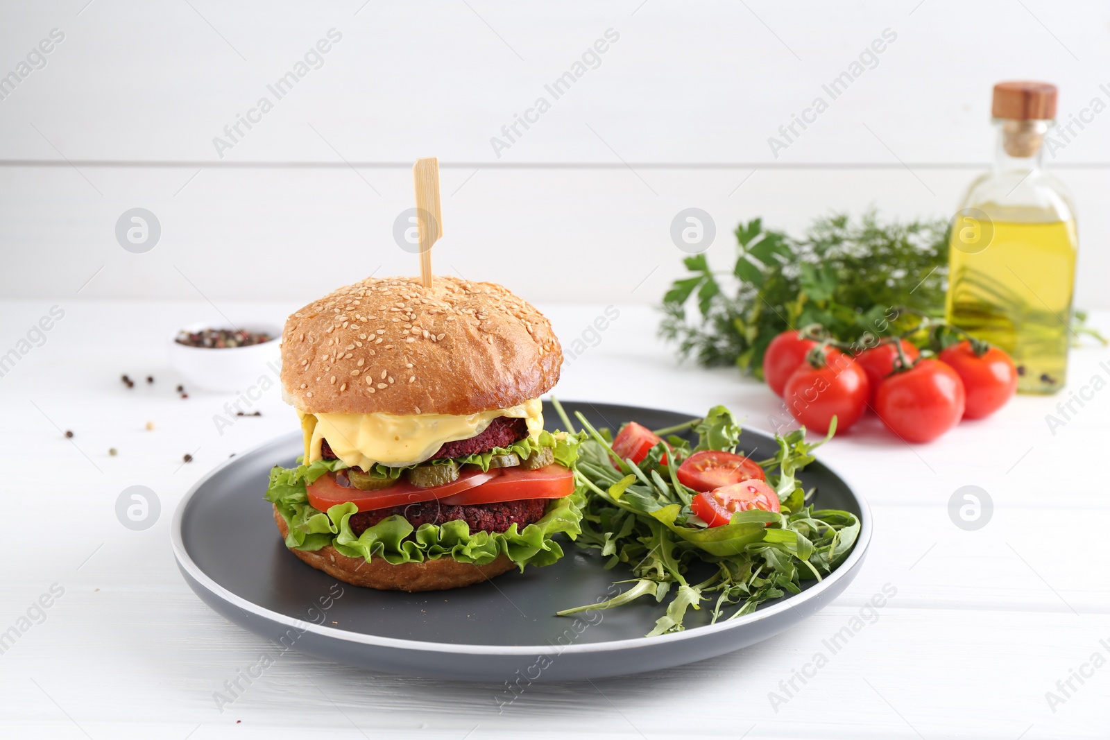 Photo of Delicious vegetarian burger served with salad on white wooden table