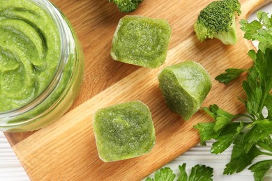 Photo of Frozen broccoli puree cubes and ingredient on cutting board, flat lay