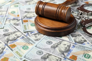 Judge's gavel and handcuffs on dollar banknotes, closeup