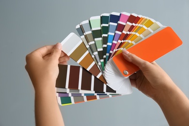 Female interior designer with palette samples on color background, closeup