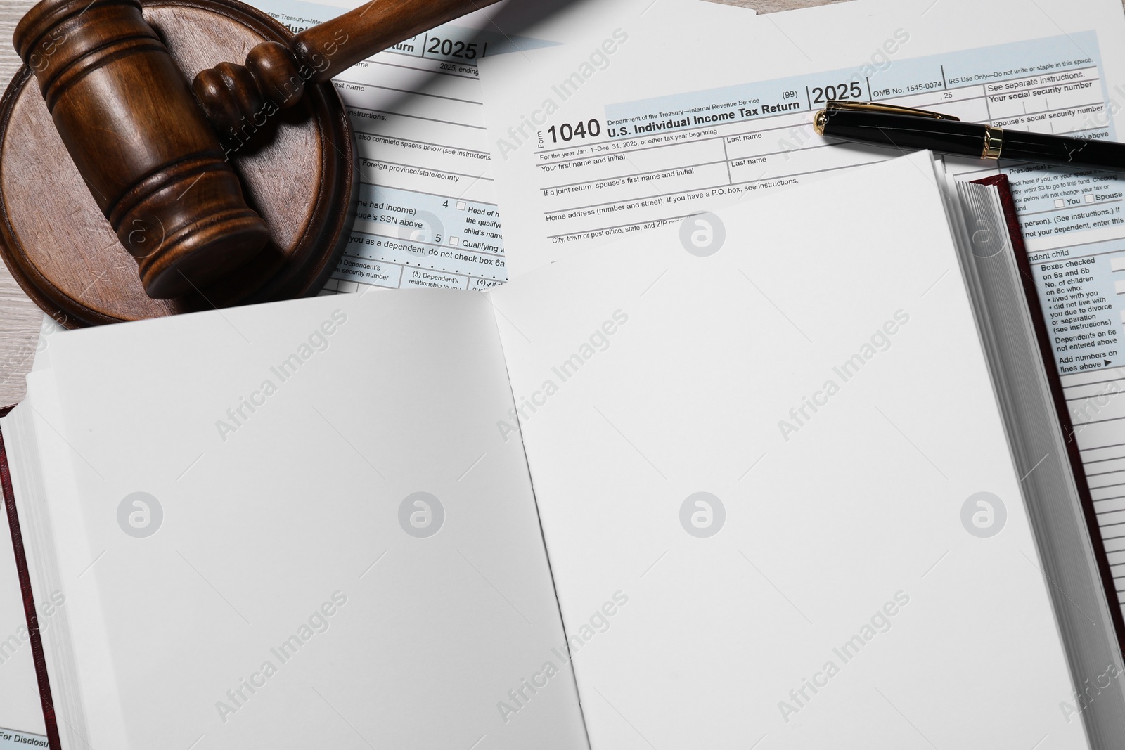 Photo of Tax return forms, open book, gavel and pen on table, top view