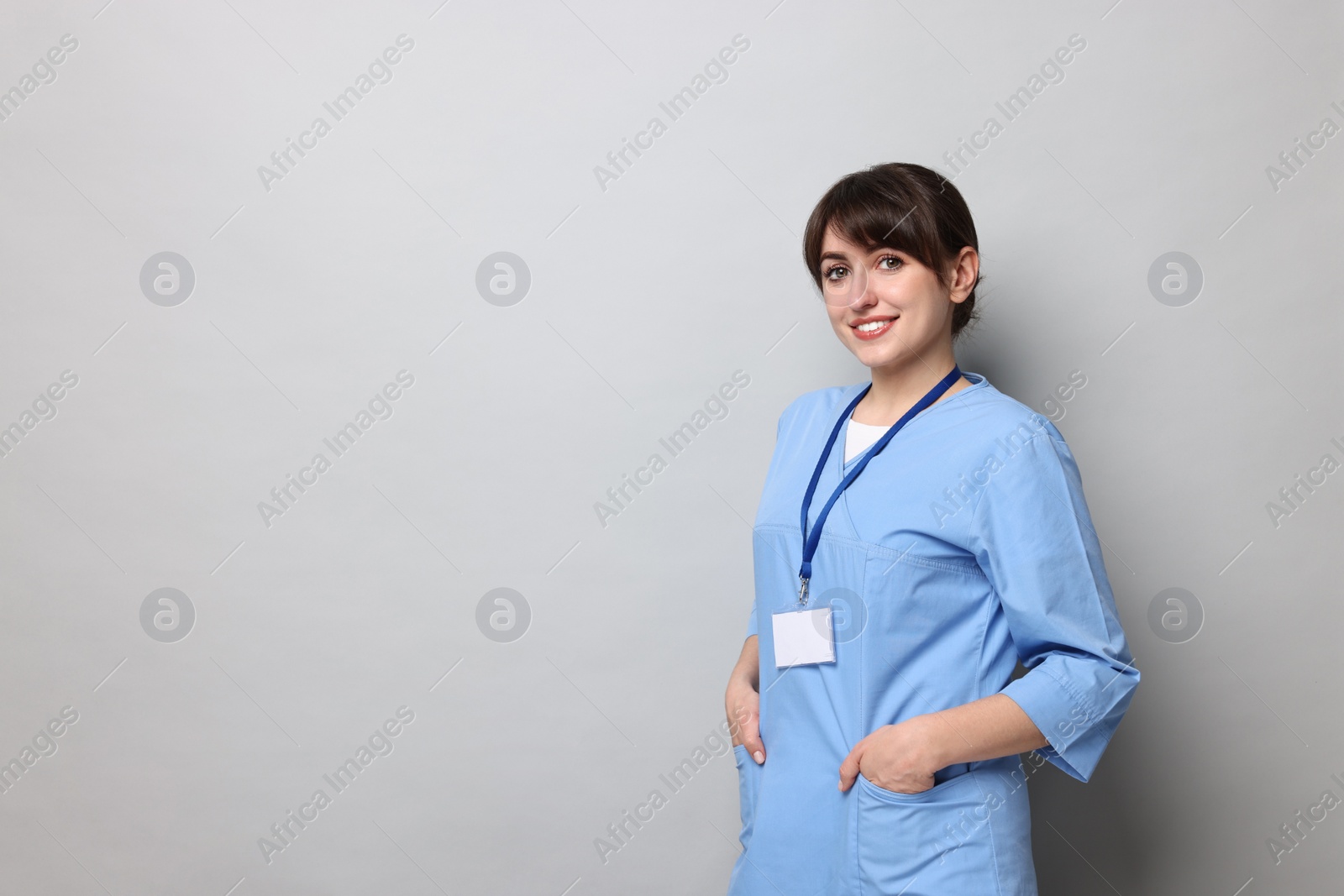 Photo of Portrait of smiling medical assistant on grey background. Space for text