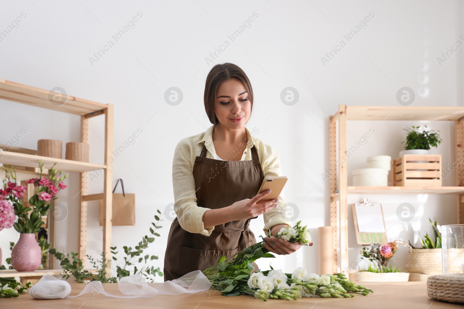 Photo of Florist taking picture of beautiful flowers in workshop