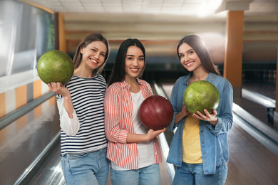 Group of young women with balls in bowling club